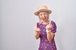 Young caucasian woman wearing flowers dress and summer hat showing middle finger doing fuck you bad expression, provocation and rude attitude. screaming excited