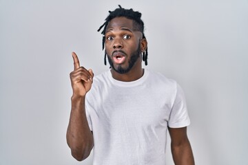 Wall Mural - African man with dreadlocks wearing casual t shirt over white background pointing finger up with successful idea. exited and happy. number one.