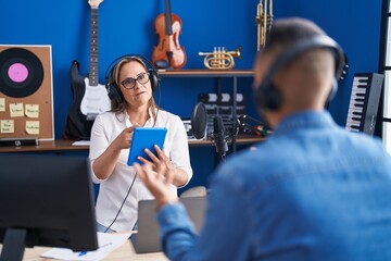 Poster - Man and woman musicians listening to music using touchpad at music studio