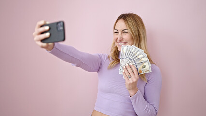 Canvas Print - Young beautiful hispanic woman taking selfie holding dollars over isolated pink background