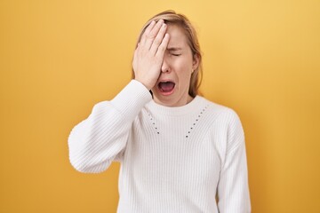 Wall Mural - Young caucasian woman wearing white sweater over yellow background yawning tired covering half face, eye and mouth with hand. face hurts in pain.