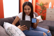 © Krakenimages.com - Young arab woman using touchpad drinking coffee sitting on sofa at home
