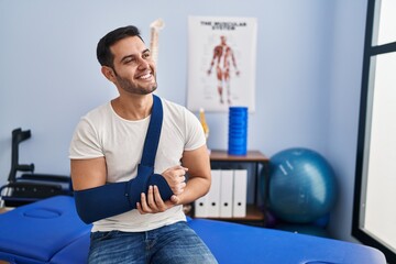 Wall Mural - Young hispanic man injured physiotherapy patient sitting on board at rehab clinic