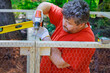 © ungvar - Worker uses screwdriver to wooden domestic chicken coop on farm that contains metal grid