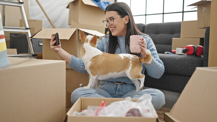 Canvas Print - Young hispanic woman with chihuahua dog taking a selfie with smartphone at new home