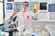 © Krakenimages.com - Hispanic girl with down syndrome working at scientist laboratory showing and pointing up with fingers number seven while smiling confident and happy.