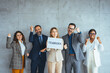 © Dragana Gordic - Portrait of multi ethnic successful business team looking at camera in the office and team leader holding sign ''teamwork'' in hands. Business men and women managers team holding big teamwork banner.