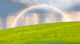 Fototapeta Tęcza - Beautiful landscape view of green grass field with rainbow - Aerial view of rain above countryside rural field or meadow landscape