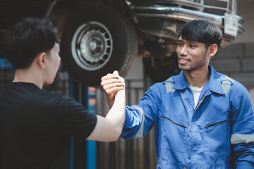 Two professional auto mechanics shaking hands, all kinds of car specialists, expert auto repair and standard auto repair center.