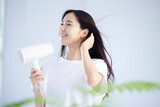 ドライヤーで髪の毛を乾かす健康的な日本人女性の夏のイメージ