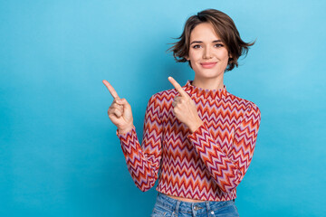 Photo portrait of attractive young woman fingers point empty space promoter wear trendy striped outfit isolated on blue color background