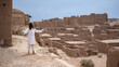 © Marek - man in white robes standing with arms open in front of a ancient city ruins in desert