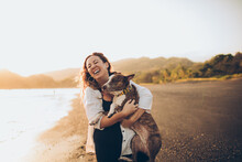 Woman Hugging Her Dog On The Beach