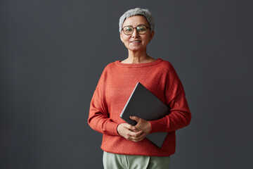 Minimal waist up portrait of smiling senior businesswoman looking at camera against wall, copy space