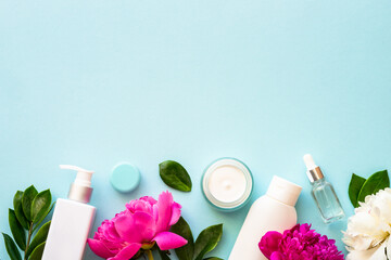 Wall Mural - natural cosmetic products. cream, serum, tonic with green leaves and flowers. flat lay on blue backg