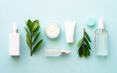 Wall Mural - natural cosmetic products. cream, serum, tonic with green leaves. flat lay on blue.