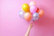 Hand holding colorful balloons on pink background, Generative AI
