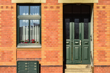 Wall Mural - View of brick building with green wooden door, window and mailboxes