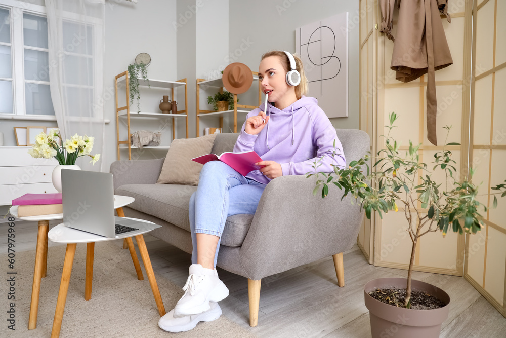 Female student in headphones doing homework at home