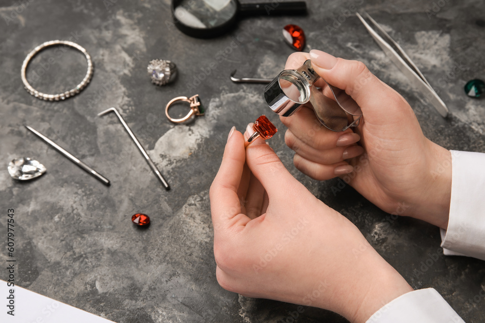 Female jeweler examining ring on dark table, closeup