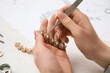 Female jeweler making adornment on white table, closeup