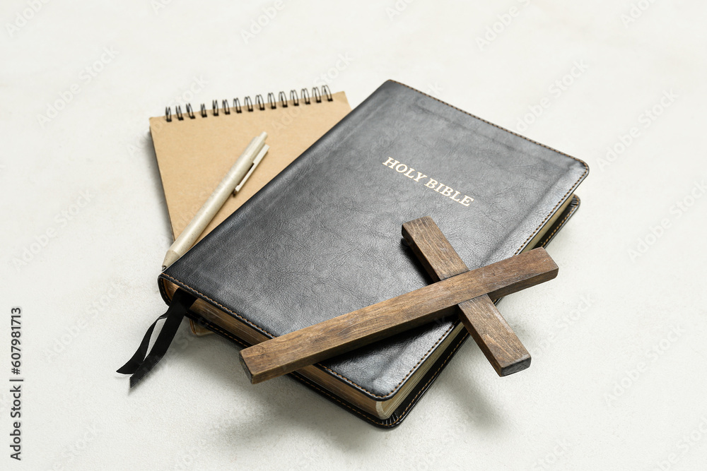 Holy Bible with wooden cross and notebook on white background