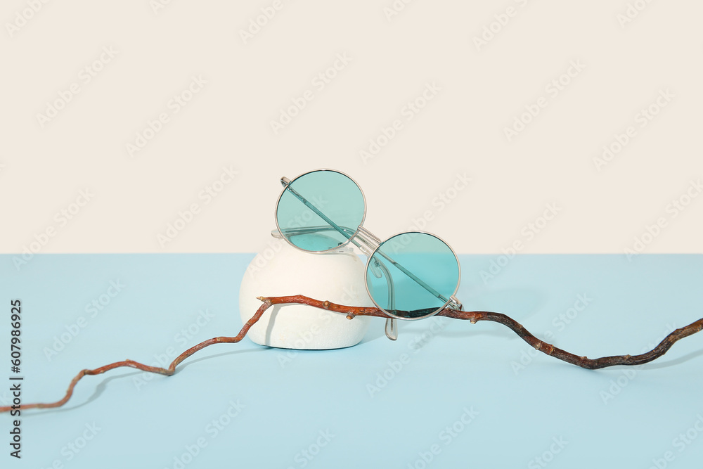 Podium with stylish sunglasses on blue table