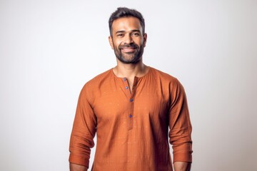 Wall Mural - Handsome bearded Indian man in orange shirt smiling on white background