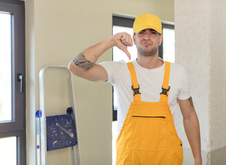 young handsome man feeling cross,showing thumbs down. handyman concept