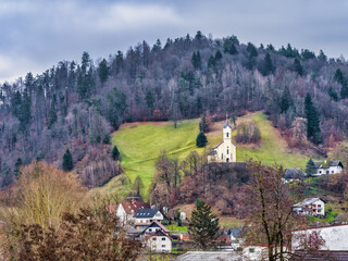 Wall Mural - A church on a hill and village houses during a cloudy afternoon in Skofja Loka, Slovenia