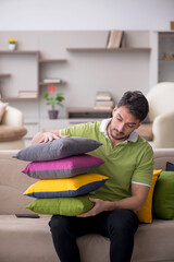 Wall Mural - Young man with a lot of pillows sitting on the sofa