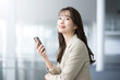 Beautiful smiling Asian woman in a suit in an office talking on her phone.