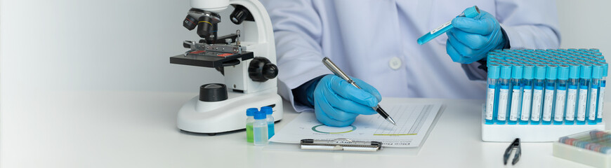 copy space, banner, panorama Scientists use scientific test tubes to record chemical data or drugs for testing and looking through a microscope in science laboratory for medicine biotechnology biology