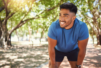 Wall Mural - Fitness, break and man or runner outdoor for exercise, training or running at a park. Happy and tired Indian male athlete in nature for a workout, run and rest while thinking of goals or performance