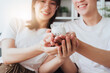 Happy asian family young couple holding piggy bank to save for saving money wealth to buy real estate for new home. Financial planning, business finance concept