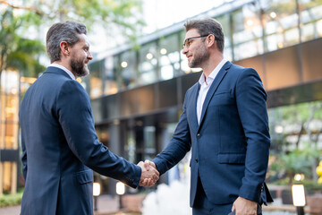 Wall Mural - Handshake with business partner in the city for greeting. Handshake between two business men. Two businessmen shaking hands on city street. Business men in suit shaking hands outdoors. Business team.