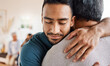 © Nicholas Felix/peopleimages.com - Father, son and hug for love, care or support in family bonding or time together in living room at home. Happy man hugging dad in reunion embrace, relationship or greeting for elderly care at house