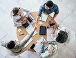 © Matthew C/peopleimages.com - Meeting, handshake and overhead with a business team sitting around a table in the office at work. Partnership, thank you and welcome with male colleagues shaking hands in agreement of a b2b deal