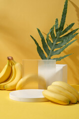 Wall Mural - Background for display cosmetic of natural extract - fresh ripe bananas and green leaf arranged on yellow background with empty white podiums. Advertising and branding cosmetic product