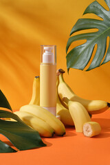 Wall Mural - Mockup scene for advertising cosmetic of banana extract - pump bottle unbranded surround by ripe yellow bananas and green monstera leaves on a yellow background with leaf shadow