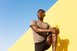 © JustLife - Young man doing stretching exercise outside. African man training outside..