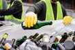 © LIGHTFIELD STUDIOS - Cropped view of blurred worker in protective gloves and vest putting glass bottle in sack people in outdoor waste disposal station, garbage sorting and recycling concept