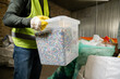 © LIGHTFIELD STUDIOS - Cropped view of worker in high visibility vest and glove holding container with plastic for recycle while working in garbage sorting center, garbage sorting and recycling concept