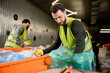 © LIGHTFIELD STUDIOS - Bearded sorter in high visibility vest and protective glove separating garbage near conveyor and blurred colleagues working together in waste disposal station, recycling concept
