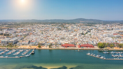 Canvas Print - Aerial view of Portuguese fishing tourist town of Olhao with a view the Ria Formosa Marine Park. Sea port for yachts and Sun over the mountains