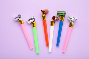 Party foil whistle or noise maker horn rolled on purple background.