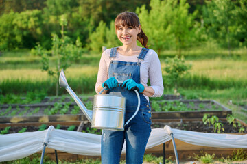 Wall Mural - Outdoor portrait of mature smiling woman with watering can