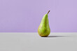 Green pear on a gray-violet background. Stylish vegan concept