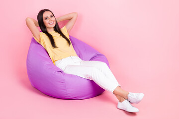 Poster - Full length photo of pretty sweet lady wear yellow t-shirt sitting bean bag arms behind head empty space isolated pink color background