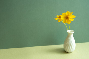 Vase of yellow flower on table. green wall background. minimal object